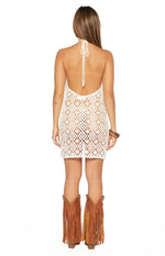 Rear view of a white crochet mini dress with a halter neck tie and a low scoop back, showing the openwork pattern