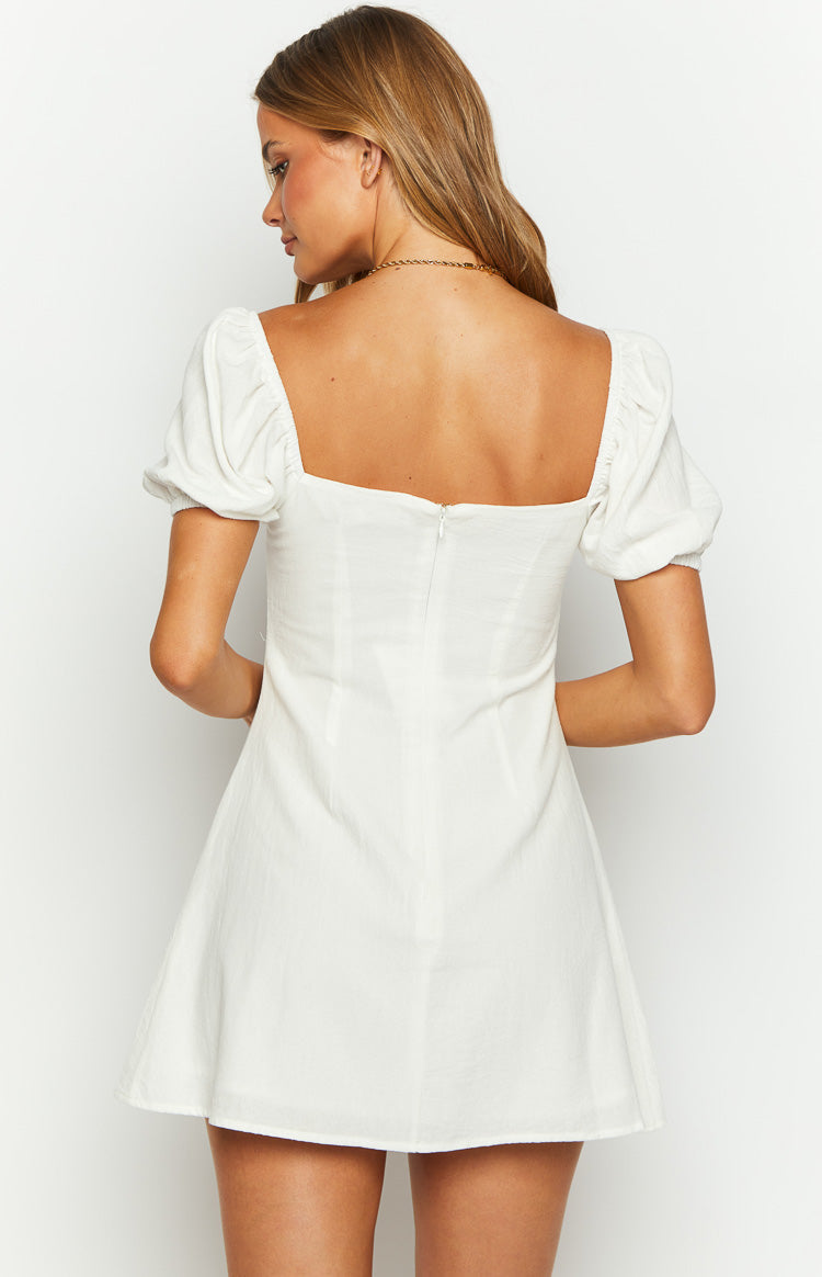 Rear view of a white textured mini dress with a square back neckline, short puff sleeves, and a center back zipper