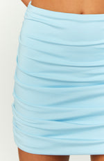 Close-up of the light blue mini skirt fabric, highlighting the horizontal ruching and soft jersey knit