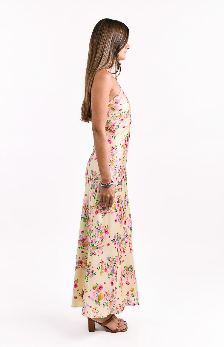 Side view of a yellow floral satin maxi dress with a fitted bodice, thin spaghetti straps, and a flowy maxi skirt
