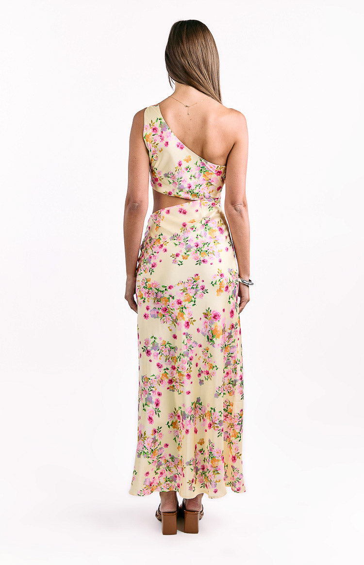 Rear view showing the one-shoulder neckline and back waist cutout of the yellow floral satin maxi dress