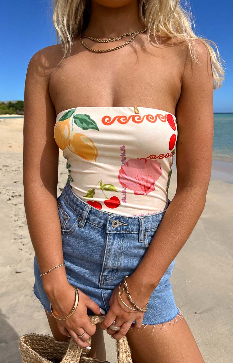 Close-up of the cream strapless bodysuit with a vibrant fruit and floral pattern including lemons and cherries
