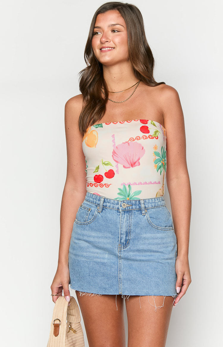 Front view of a cream strapless bandeau bodysuit with a colourful fruit and shell print and scalloped top edge