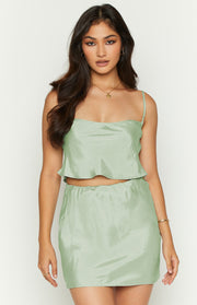 Front view of the sage green shimmery satin crop top with a straight neckline, thin spaghetti straps, and a relaxed hem