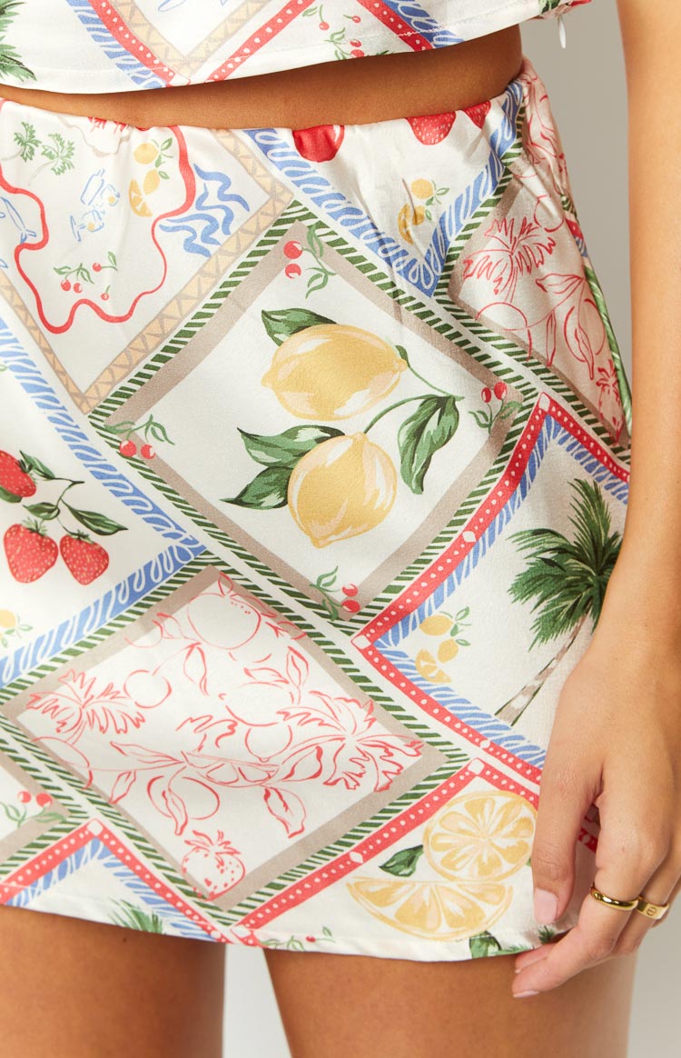 Close-up of the white satin skirt's Roma print with lemons, strawberries, palm trees, and blue and red borders
