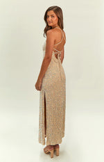 Rear view of a gold sequin maxi dress featuring criss-cross back straps, a tie-back, and a high side slit