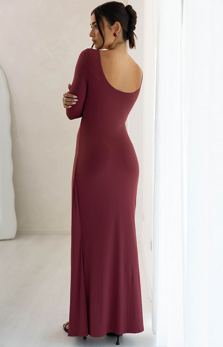 Side view of a burgundy long sleeve maxi dress showing the low scoop back and fitted silhouette