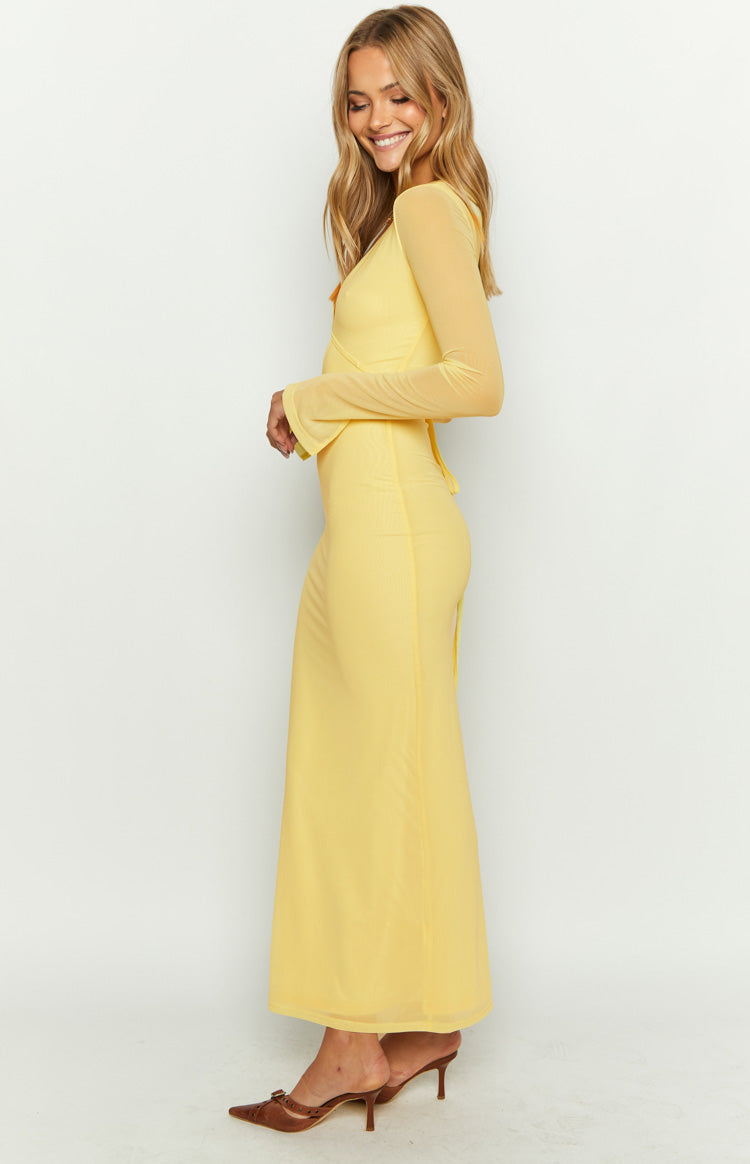 Side view of a yellow maxi dress with sheer long sleeves, flared cuffs, and a wrap-style bodice with back ties
