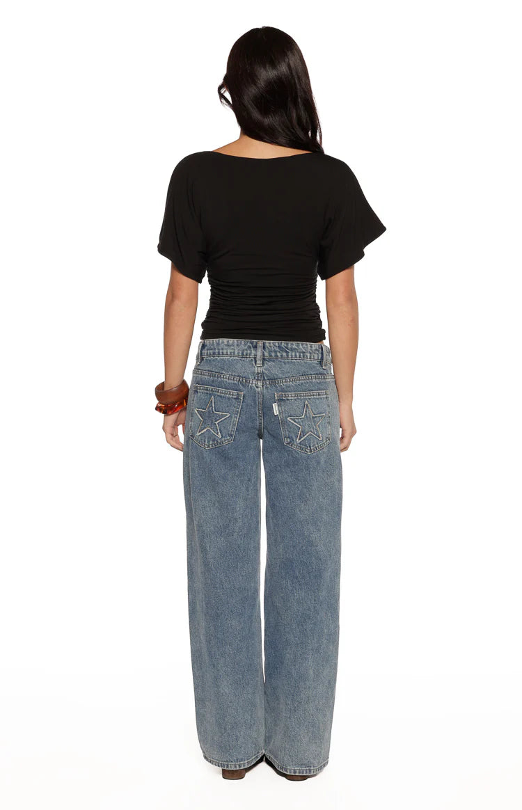 Rear view of a black jersey top with a boat neck, short loose sleeves, and ruched waist detail