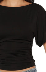 Close-up of the black jersey top showing the boat neckline, short sleeves, and side ruched waist