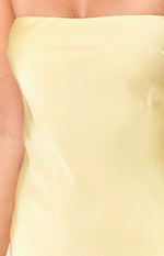 Close-up of the smooth yellow satin fabric of the strapless mini dress bodice