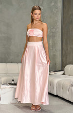 Full length view of a pink satin high-waisted maxi skirt with a wide waistband and soft pleats
