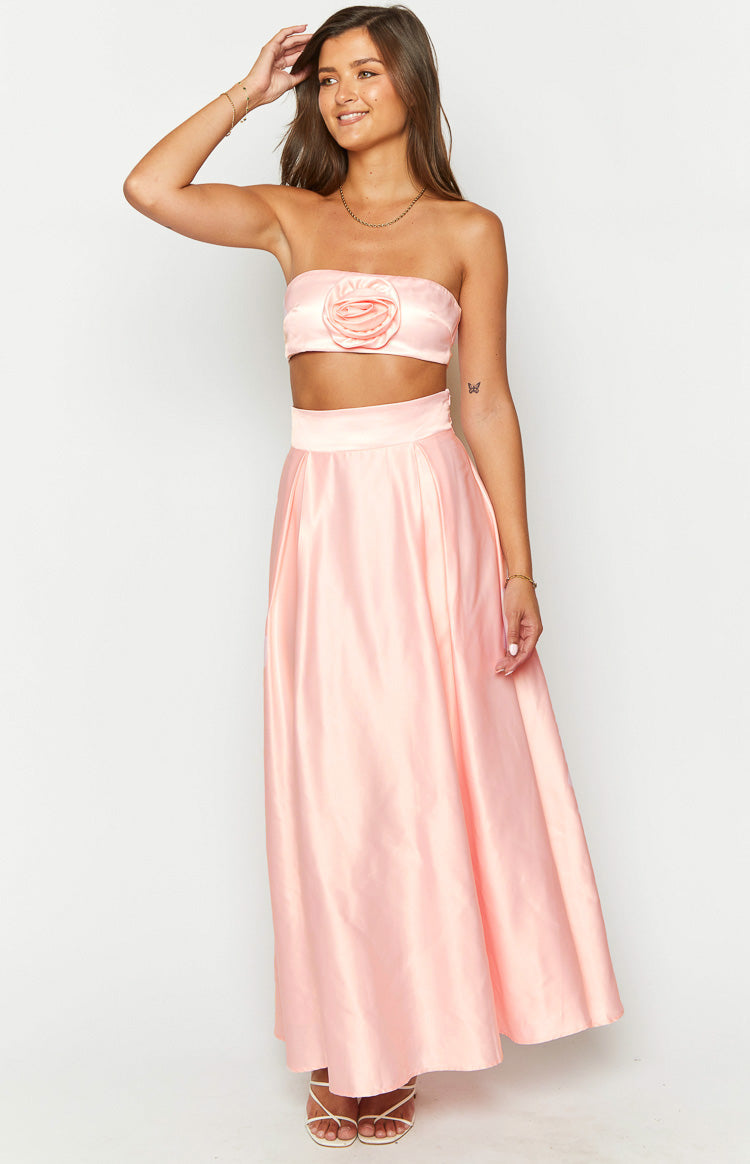 Full front view of a pink satin high-waisted maxi skirt with a wide waistband and pleated, flowing design