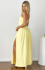 Side view of a yellow strapless maxi dress with a fitted bodice, gathered waist, and a high thigh split