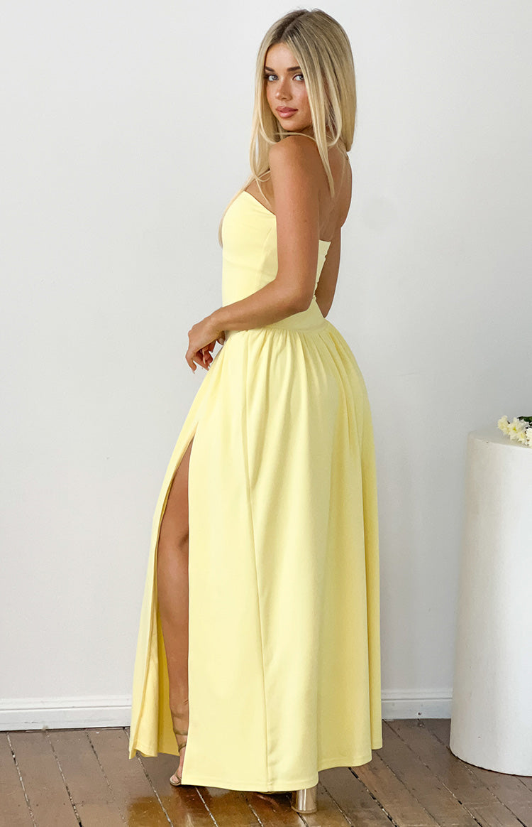 Side view of a yellow strapless maxi dress with a fitted bodice, gathered waist, and a high thigh split