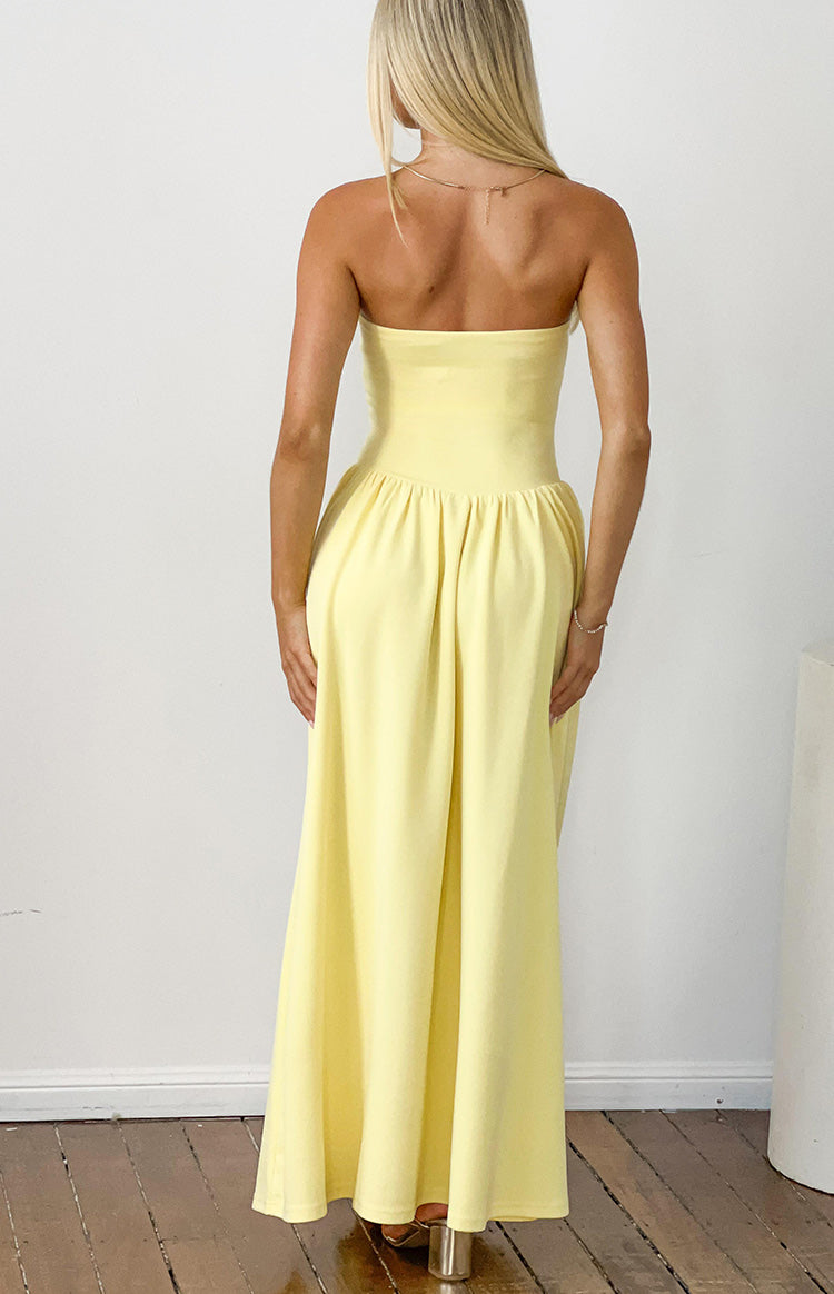 Rear view of a yellow strapless maxi dress with a fitted bodice and gathered flowing skirt