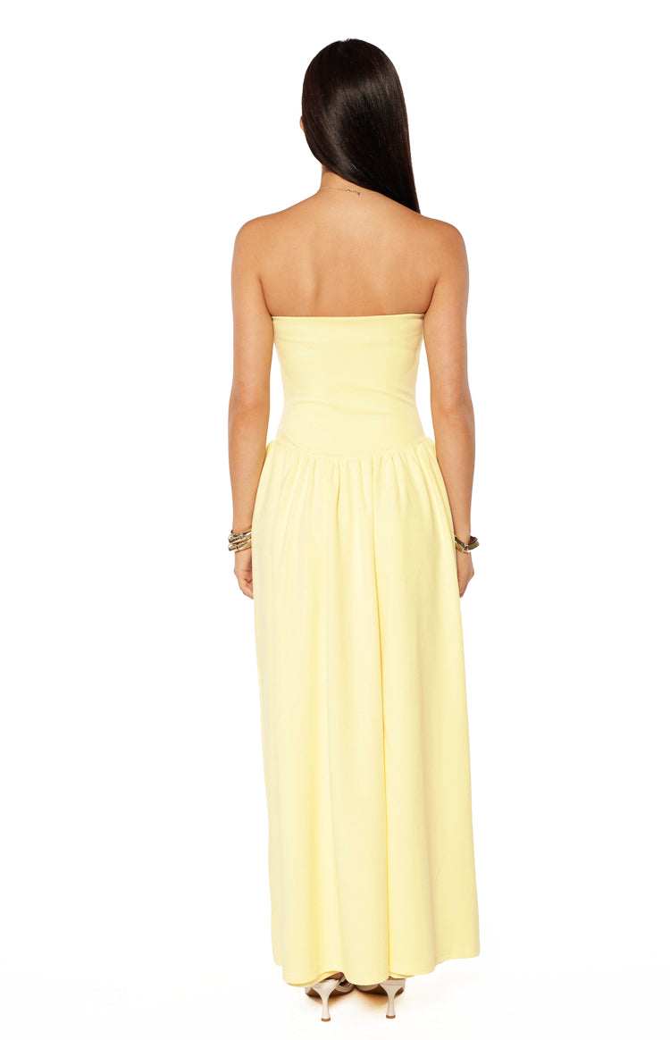 Rear view of a yellow strapless maxi dress with a fitted bodice and gathered flowing skirt