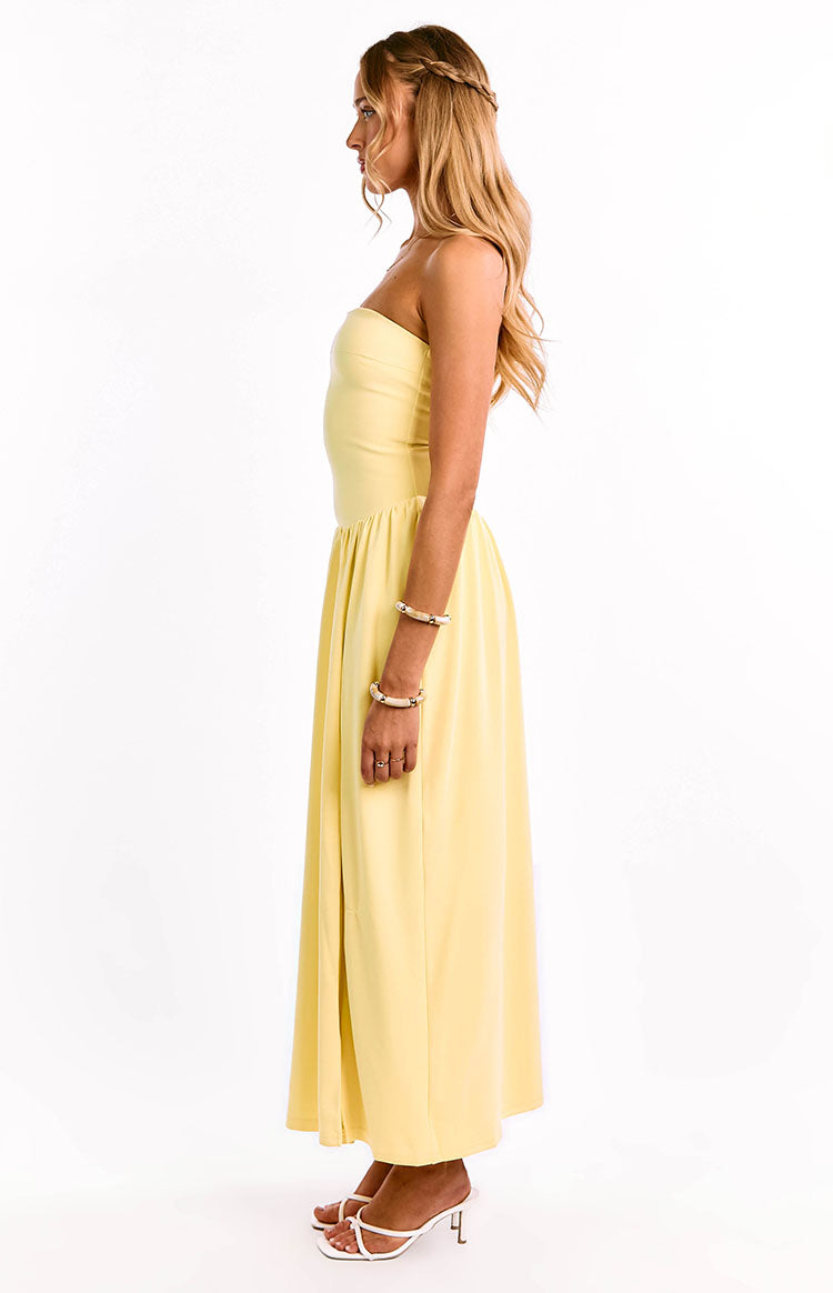 Side view of a yellow strapless maxi dress with a fitted bodice and a gathered, flowy skirt