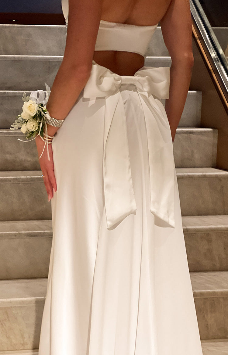 Rear view of a white maxi dress with a large satin bow at the back waist and a cutout detail