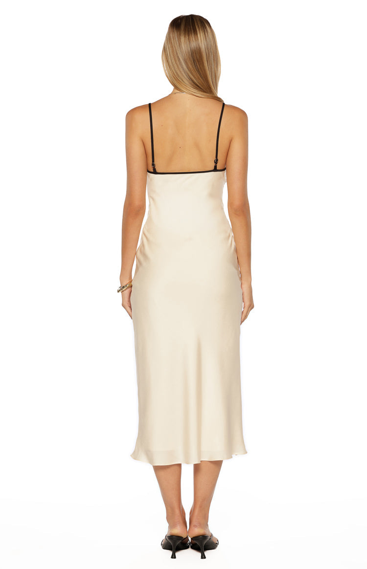 Rear view of a cream satin midi dress with thin black adjustable spaghetti straps and black trim