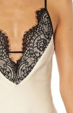 Close-up of the cream satin V-neckline with black floral lace trim, horizontal strap, and side zipper