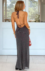 Rear view of a black polka dot maxi dress with an open back, halter neck tie, and adjustable tie-back detail