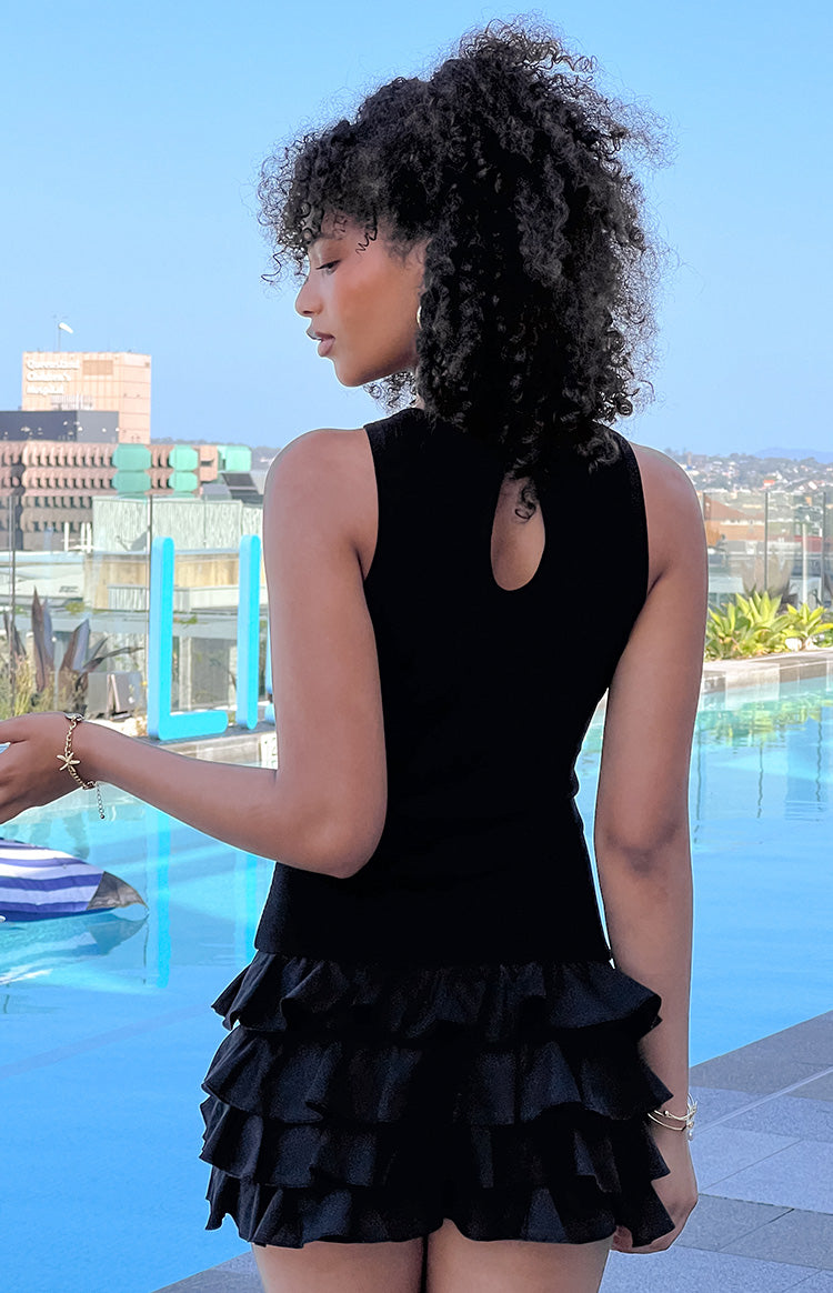 Rear view of a black sleeveless playsuit with a keyhole back and tiered ruffle shorts