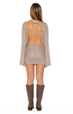 Rear view of a brown sheer mesh mini dress with a low scoop back, tie-back, flared long sleeves, and studded hem