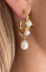 Close-up of a gold textured hoop earring with three small embedded freshwater pearls and one large dangling pearl
