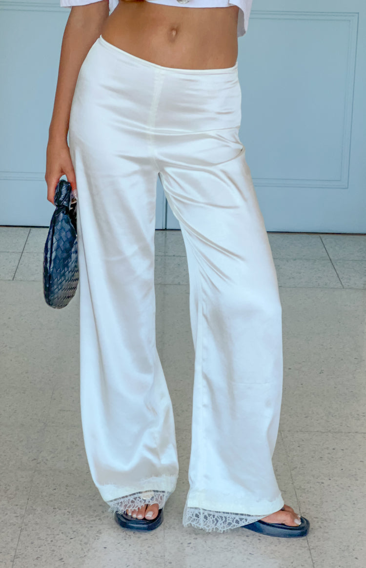 Ivory satin straight leg pants with delicate lace trim visible at the ankle hem