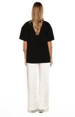 Rear view of ivory satin straight leg pants with delicate lace trim at the hem
