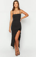 Black maxi dress with straight neckline, thin spaghetti straps, ruffled thigh-high split, and rosette detail