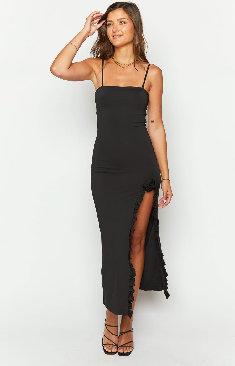 Black maxi dress with a high thigh split featuring ruffled trim and a rosette detail
