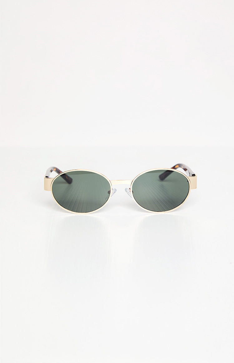 Slightly angled front view of gold frame oval sunglasses with dark green lenses and tortoiseshell arms