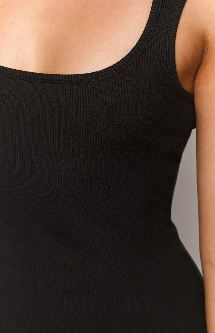 Close-up of the black ribbed knit fabric and square neckline of the mini dress