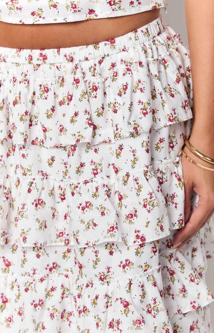 Close-up of the elasticated waist and tiered ruffles of a white maxi skirt with red and yellow floral print