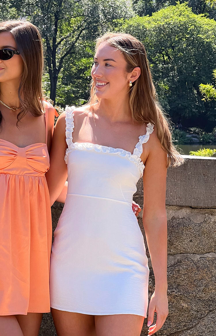 Close-up of the white mini dress bodice with a square neckline and delicate ruffled shoulder straps