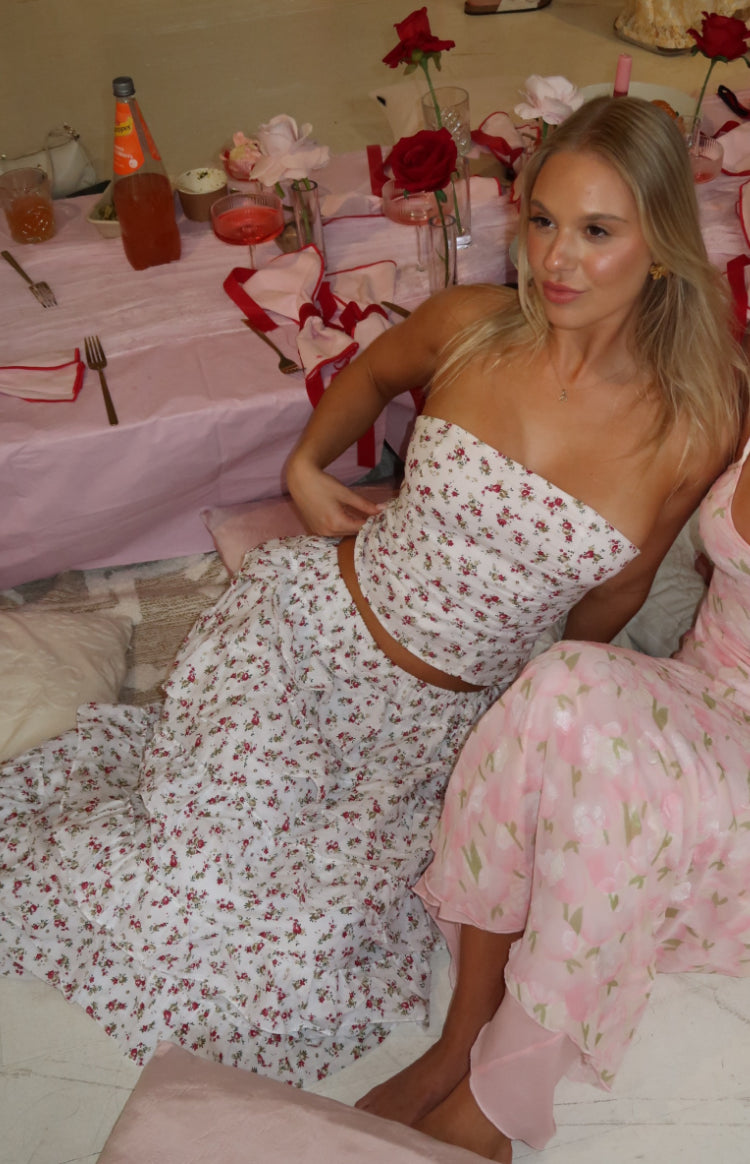 Flowy white floral maxi skirt with tiered ruffles, seen from a seated position