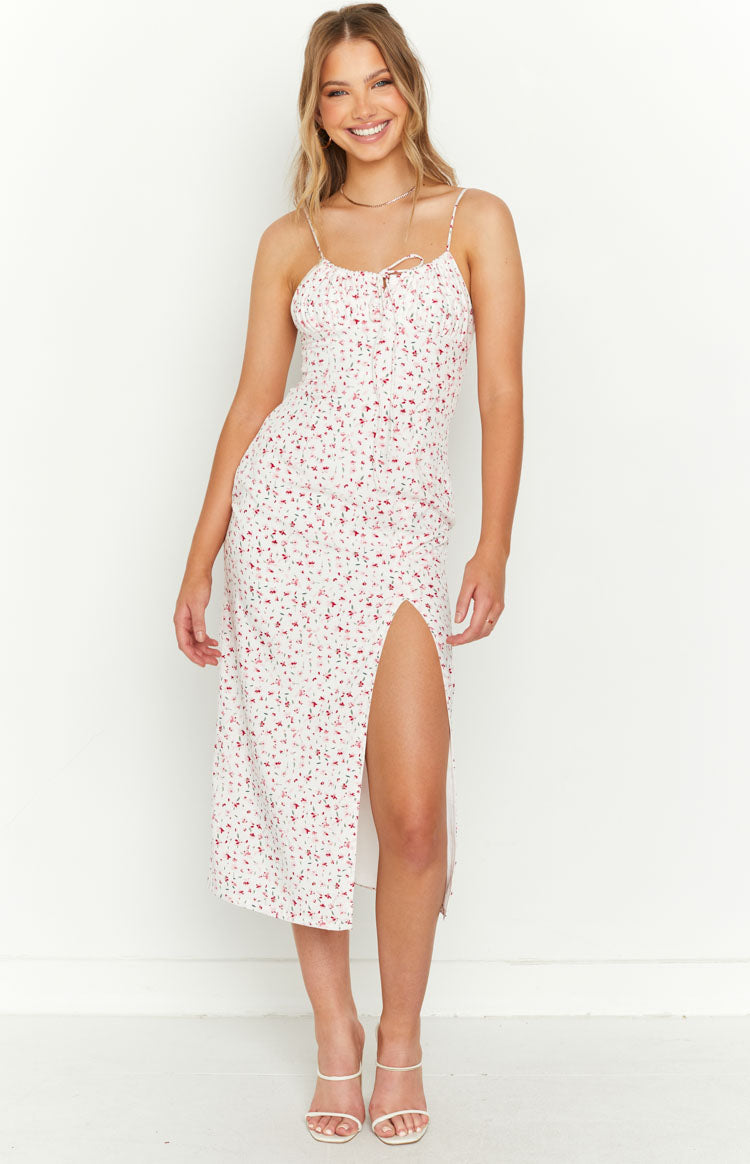 Front view of the white midi dress with red floral print, ruched bodice, tie-front sweetheart neckline, and a high left leg slit