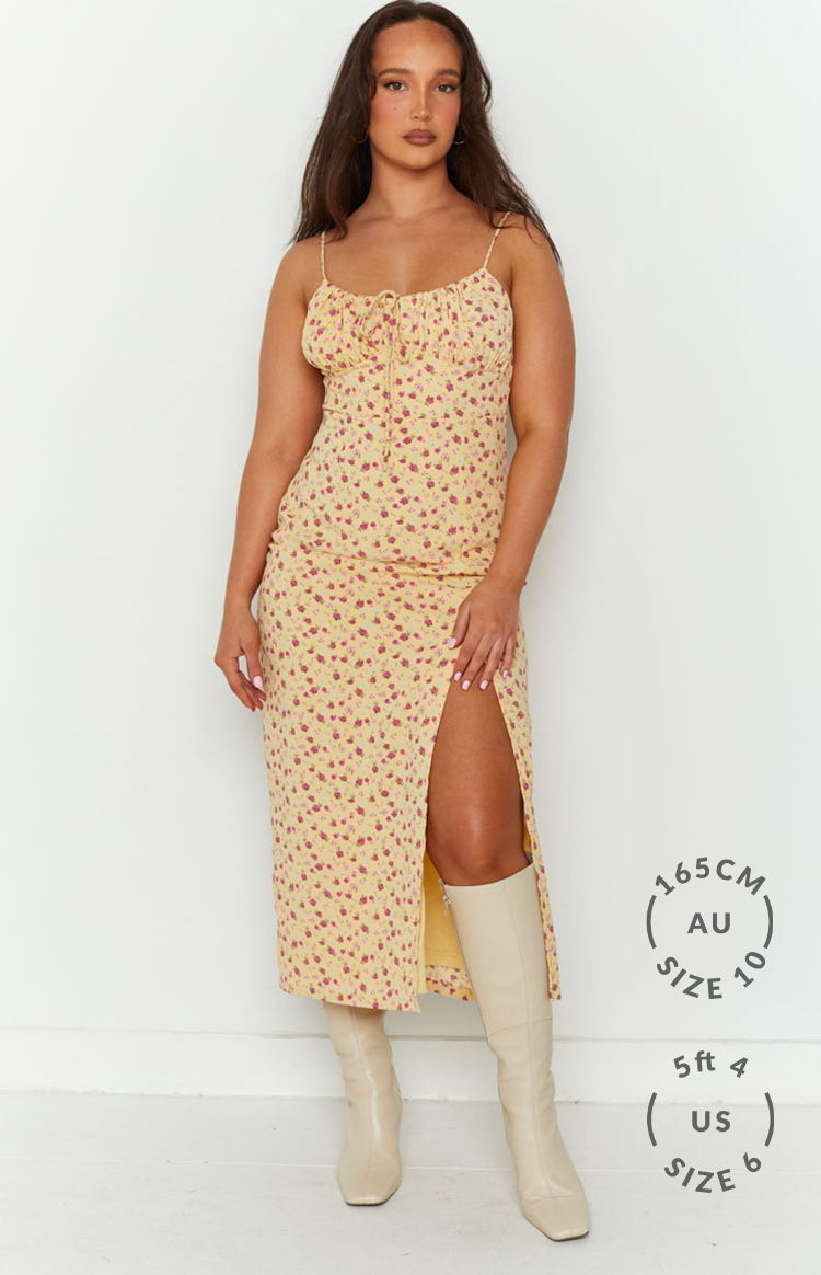 Front view of a yellow floral midi dress with spaghetti straps, a tie-front bust, and a high leg slit