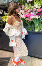 Side view of a yellow floral midi dress with a ruched bust and thin spaghetti straps