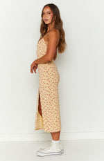 Side view of a yellow floral midi dress with a high side slit and thin spaghetti straps