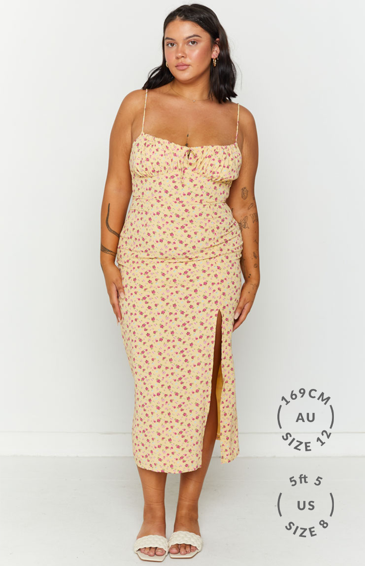 Front view of a yellow floral midi dress with a sweetheart neckline, ruched bodice, and a high left leg split