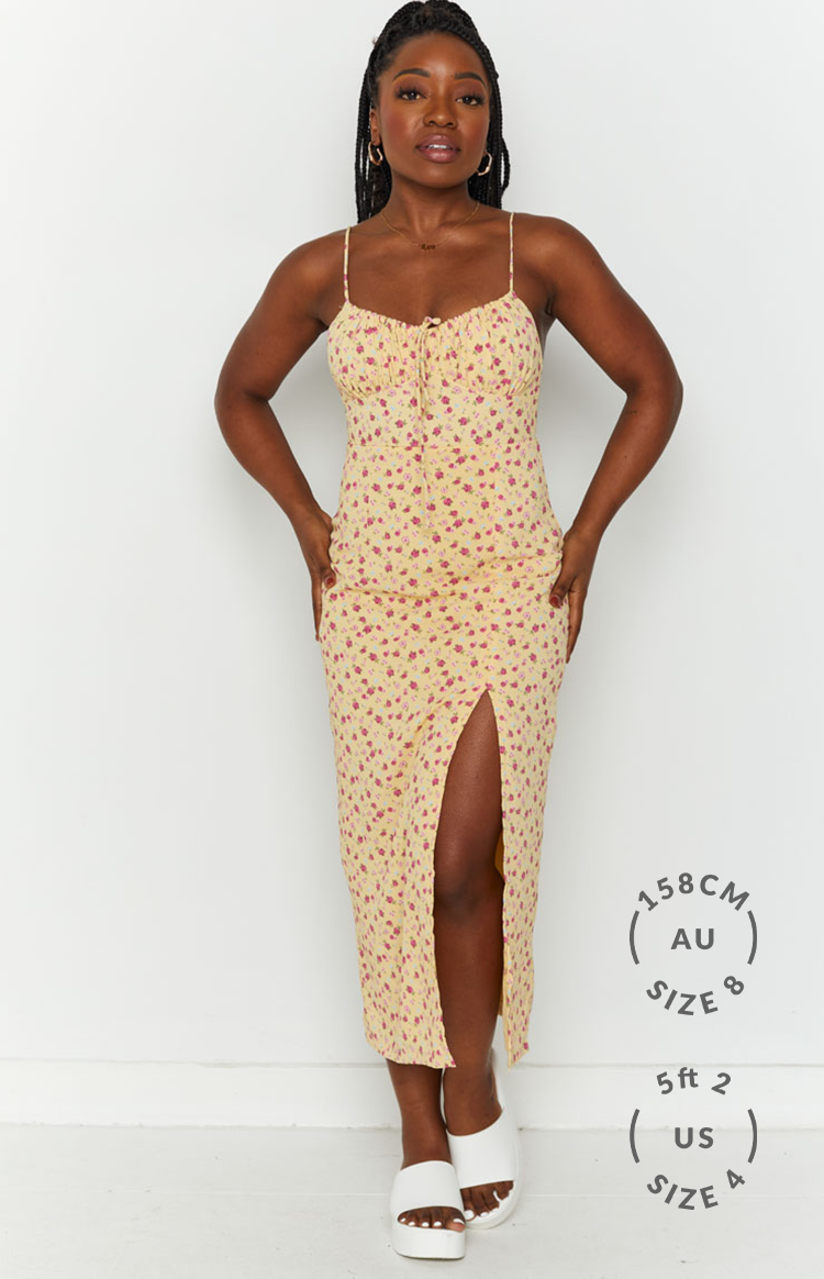 Front view of a yellow floral midi dress with a high leg split and ruched tie-front bust