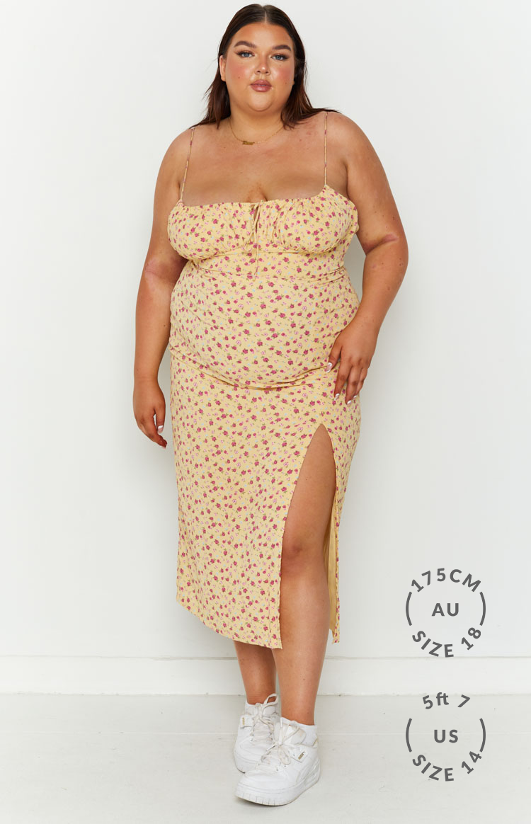 Yellow floral midi dress with a sweetheart tie-front neckline, thin straps, and a high side slit