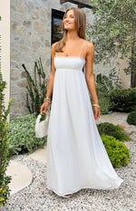 White maxi dress with a straight neckline, delicate lace trim, empire waist, and a flowy satin skirt