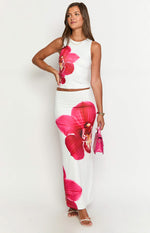 White fitted maxi skirt with a large pink orchid print and floor-length hem
