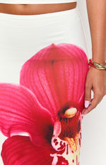 Close-up of the vibrant red orchid print on the white maxi skirt, showing the detailed petals and smooth fabric