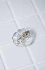 Clear shell hair clip with two white pearls, a gold star, and silver flakes embedded inside