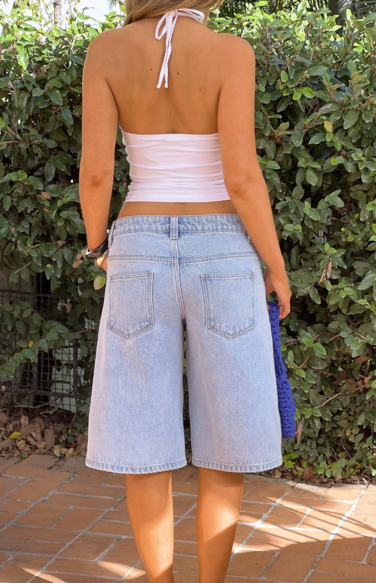 Rear view of light wash denim shorts with two back pockets and a wide-leg, knee-length fit